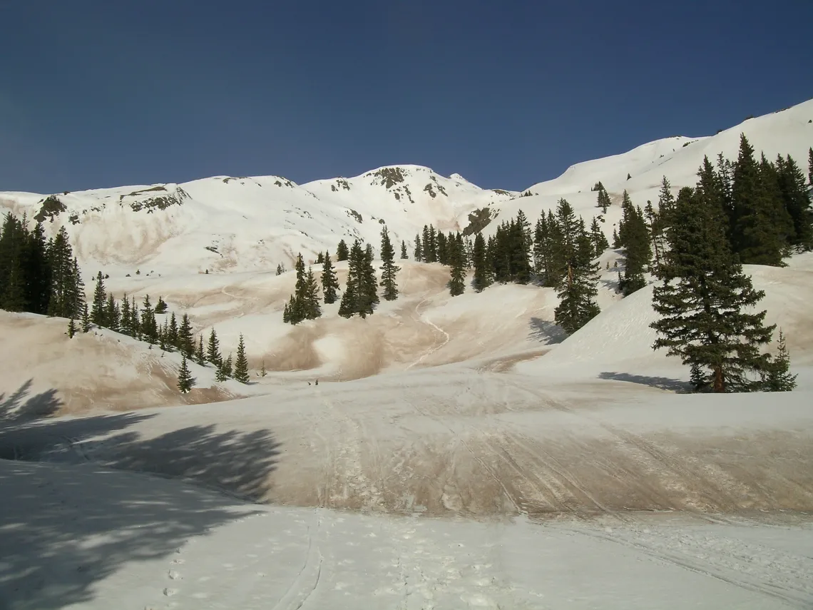 Wind-blown dust accumulation in the Rocky Mountains snowpack increases the sunlight absorbed by the snow, leading to earlier and rapid snowmelt.